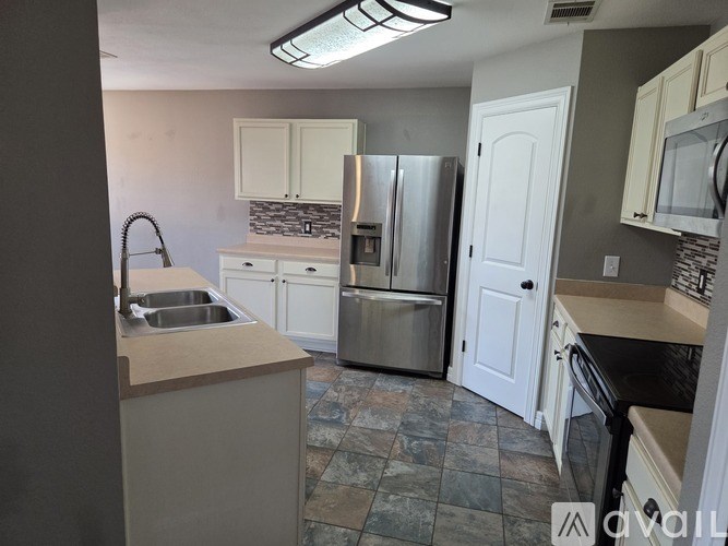 A kitchen with a sink, refrigerator, and cabinets.