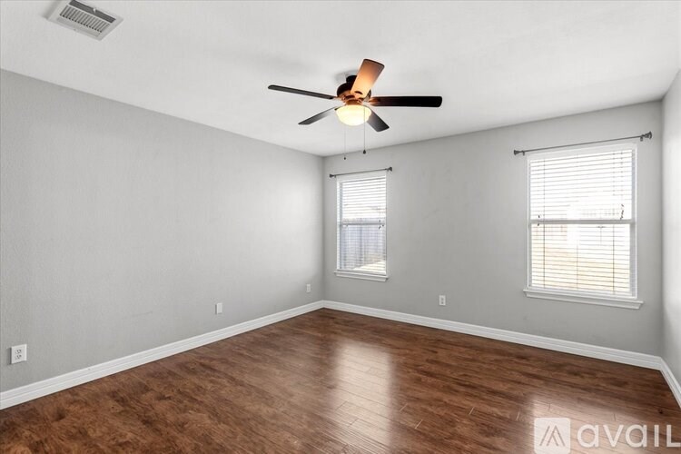 A room with a ceiling fan and wooden flooring.