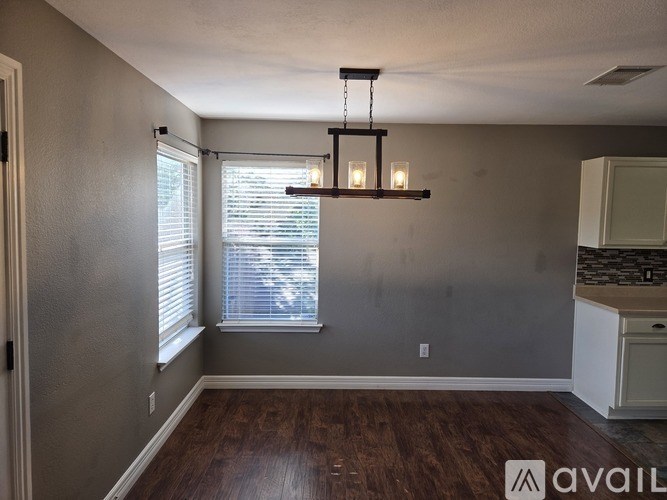 A room with a wooden floor and a window with blinds.