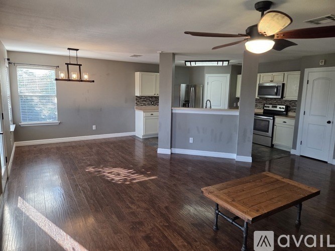 A room with a ceiling fan and a table in the middle.