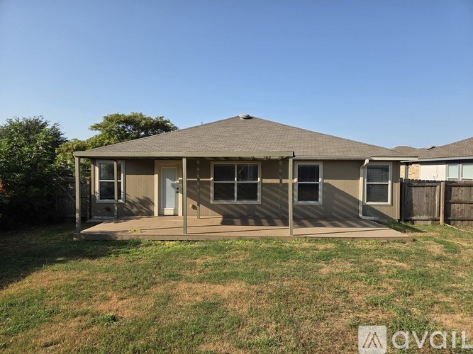 A house with a brown roof and a white door is surrounded by a grassy area.