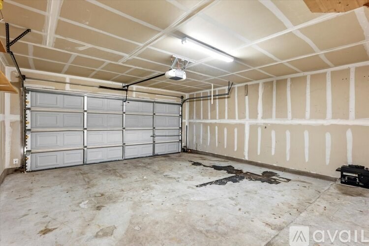 A spacious garage with a white ceiling and a large white door is available for rent.