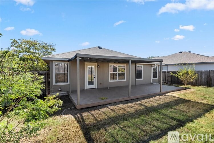 A small house with a grey roof and a deck in the backyard.