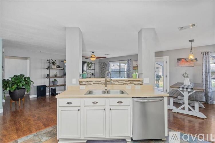 A kitchen with a white countertop and cabinets, a sink, and a dishwasher.