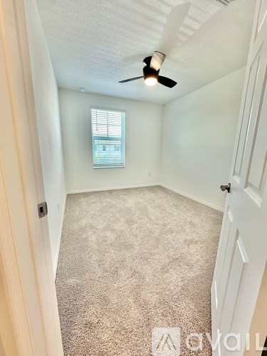A room with a carpeted floor and a ceiling fan.