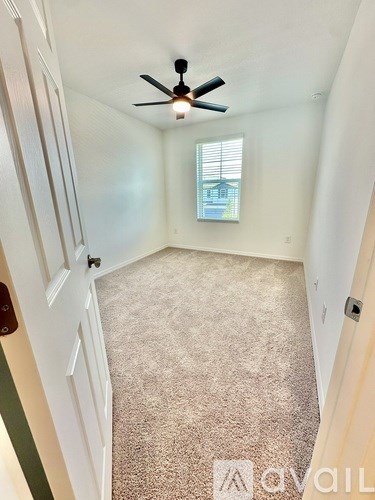 A room with a ceiling fan and carpeted floor.