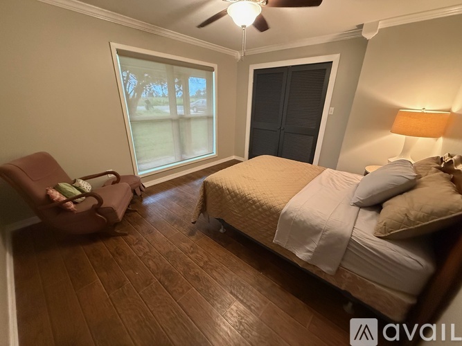 A bedroom with a bed, chair, and window.