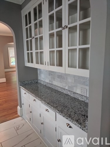 A kitchen with white cabinets and a granite countertop.