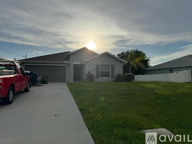 A house with a brown roof and a garage door is surrounded by greenery.