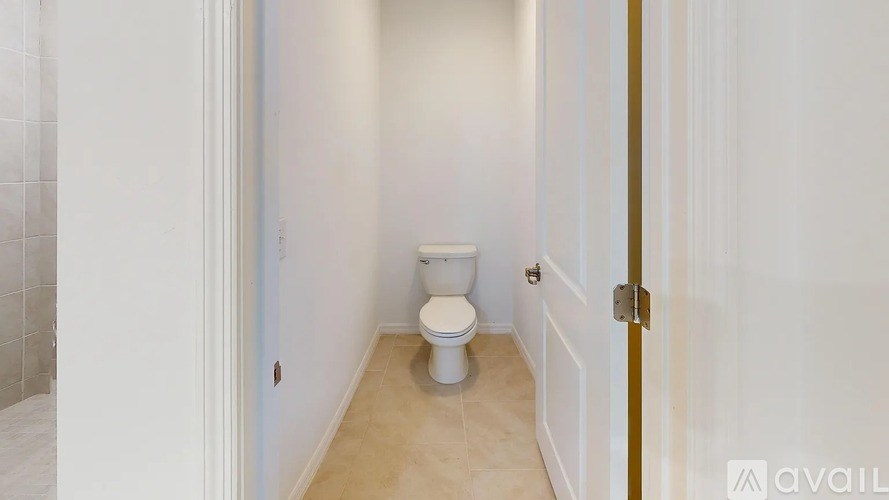 A white toilet in a small bathroom with a door on the right.