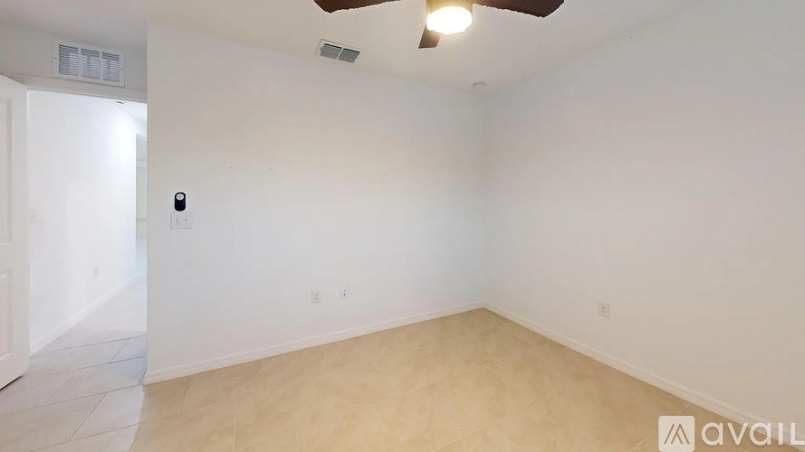 A room with a ceiling fan and a light switch on the wall.