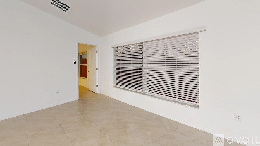 A room with a door and a window with blinds.