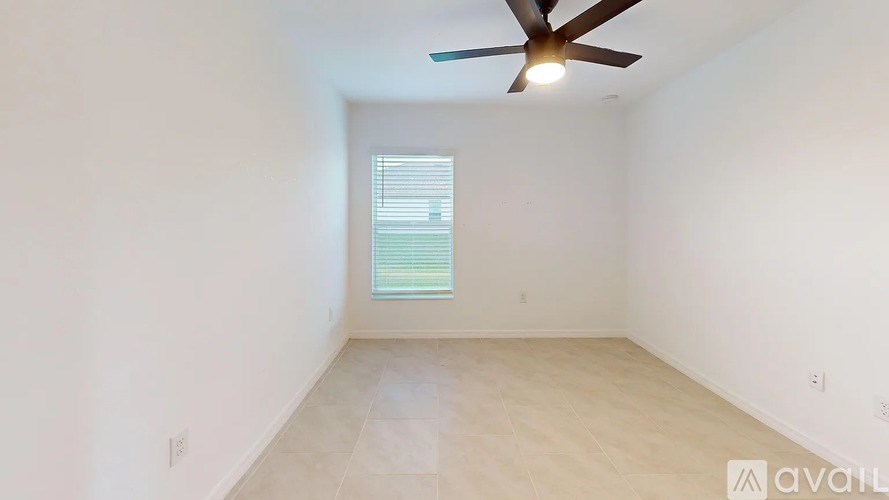 A room with a ceiling fan and a window with blinds.