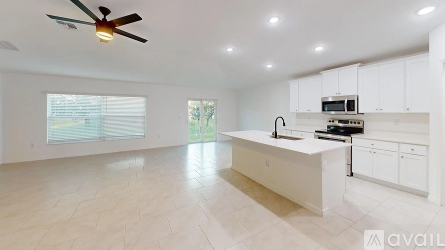 A spacious kitchen with white cabinets and a fan on the ceiling.