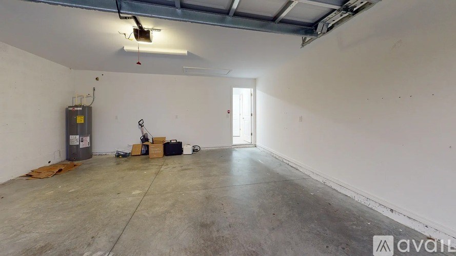 A large empty room with a door on the right and a trash can on the left.