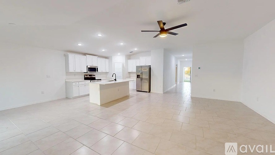A spacious living room with a kitchen area in the background.