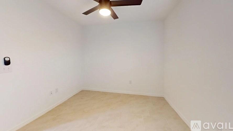 A room with a ceiling fan and a light switch on the wall.