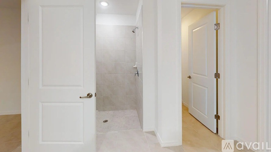 A white door is open to a bathroom with a tiled shower.