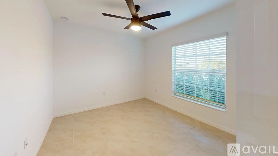 A room with a ceiling fan and a window with blinds.