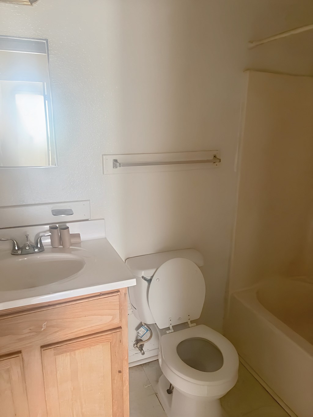 A white toilet is in a bathroom with a sink and mirror.