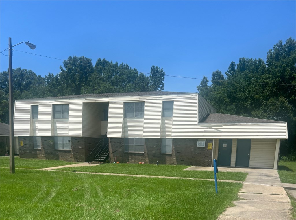 A building with a grey roof and white walls with a small porch.