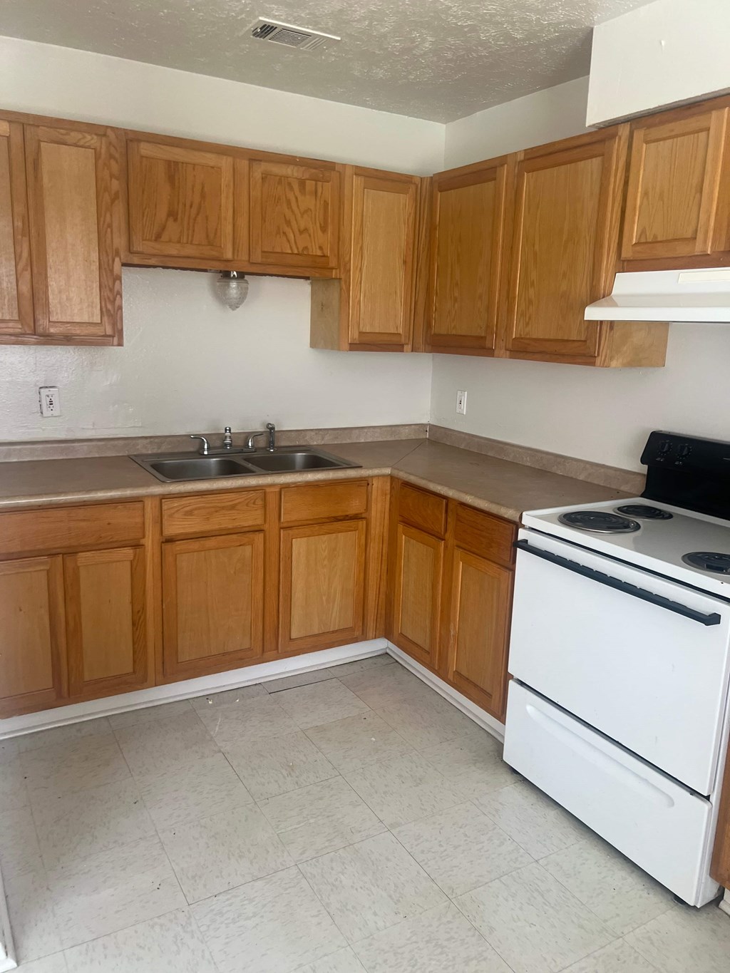 A kitchen with wooden cabinets and a white stove.