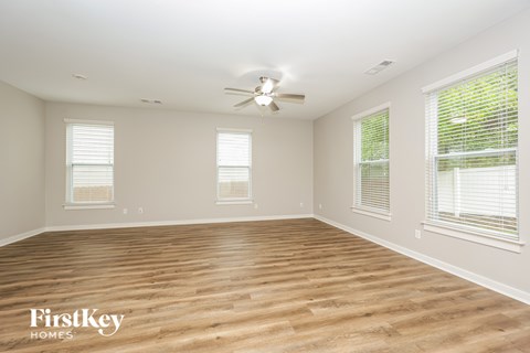 A spacious room with wooden flooring and a ceiling fan.