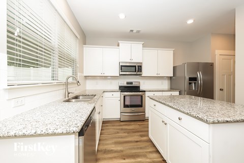 A kitchen with white cabinets and granite countertops.
