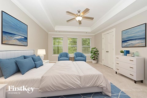 A bedroom with a large bed, a ceiling fan, and two paintings on the wall.