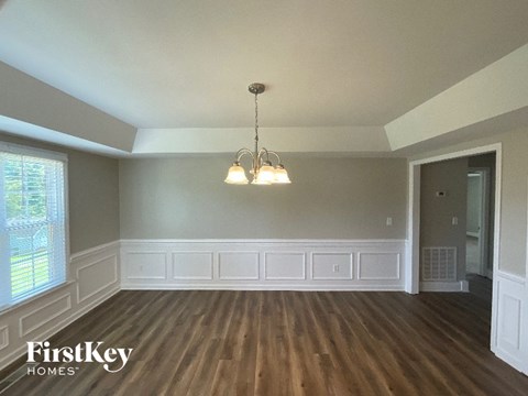 A room with wooden floors and a chandelier hanging from the ceiling.