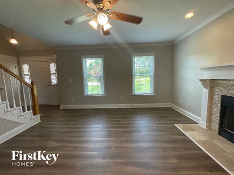 A spacious living room with a fireplace and a ceiling fan.