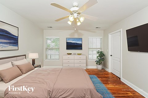 A bedroom with a bed, dresser, and a ceiling fan.