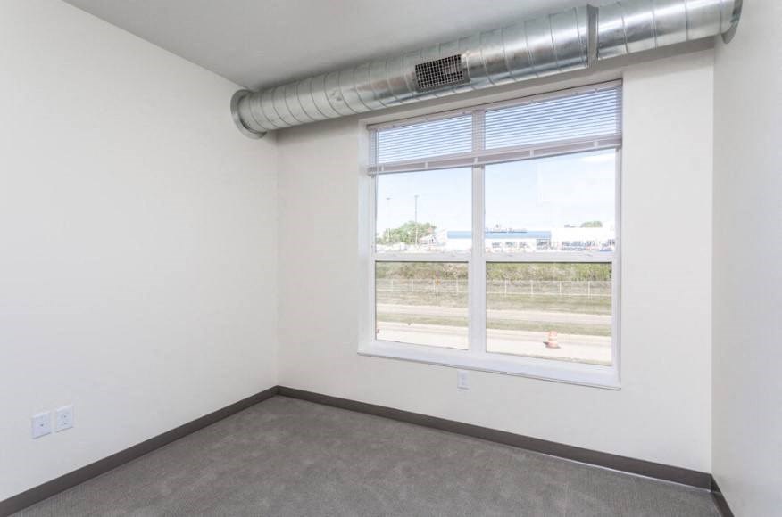 A room with a window and a view of a parking lot outside.