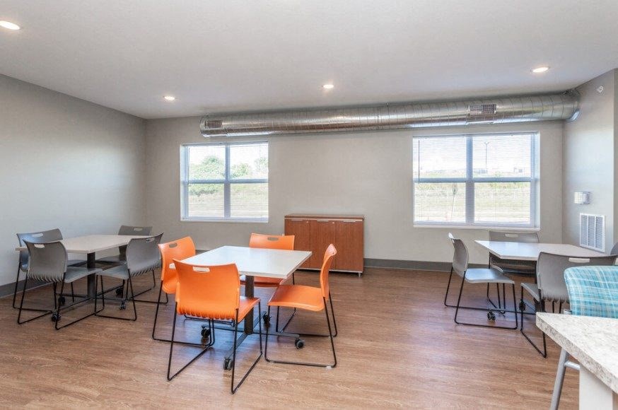 A room with tables and chairs and a window.