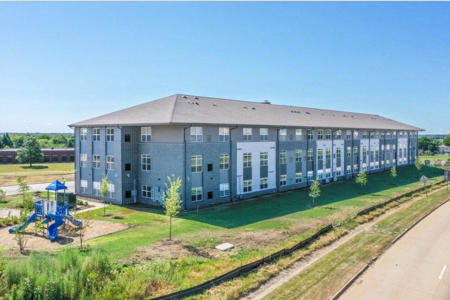 A large grey building with a playground in front of it.