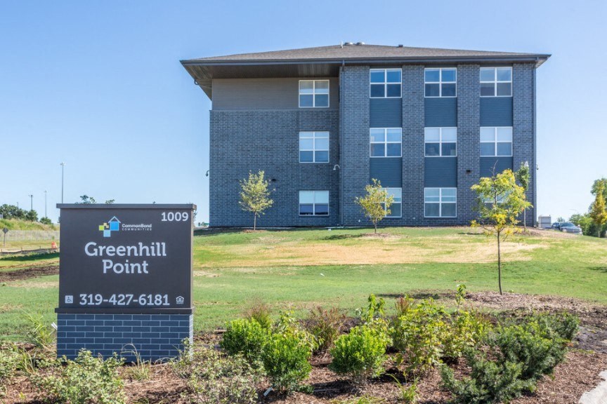 A sign for Greenhill Point with a building in the background.