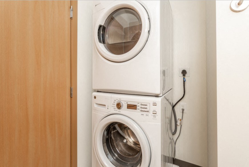 A white washing machine is placed in a small room.