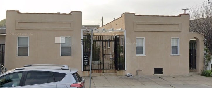 A tan building with a black gate in front.