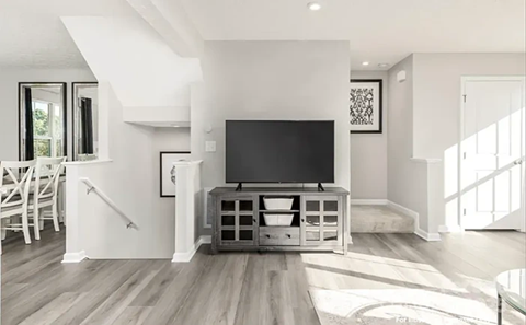 A modern living room with a television and a wooden floor.