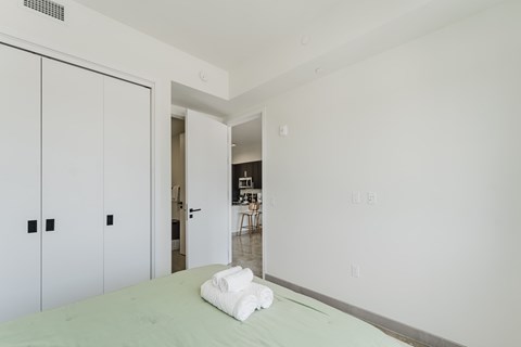 A white bedroom with a bed and a white towel on it.
