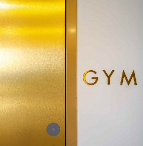 A white door with a gold Gym sign on it.
