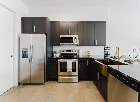 A kitchen with black cabinets and stainless steel appliances.