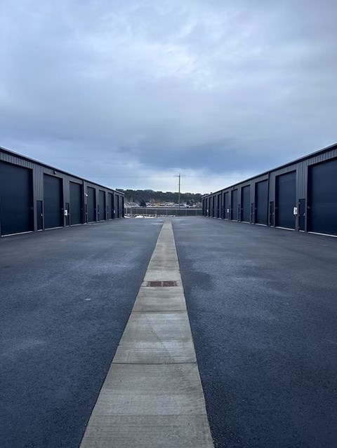 A long row of dark blue garage doors on either side of a concrete walkway.