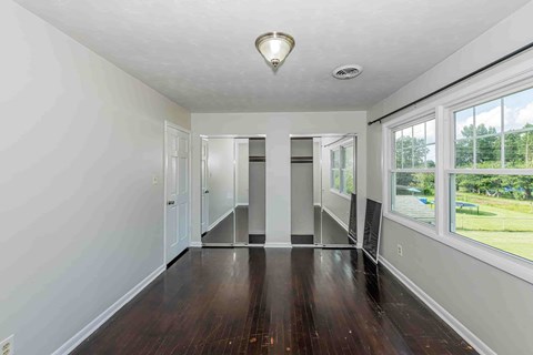 A spacious room with wood floors and a large window.