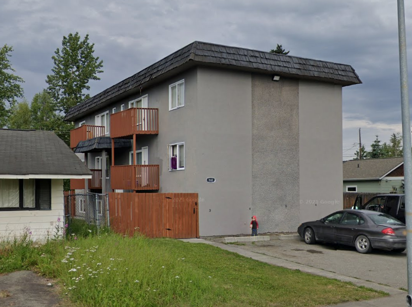 A grey building with a brown fence in front of it.