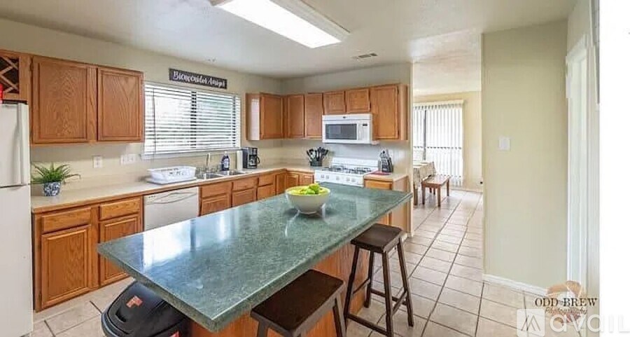 A kitchen with a green island and wooden cabinets.