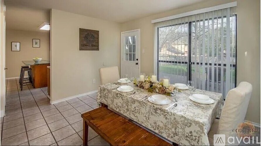 A dining room with a table set for two and a view of the backyard.