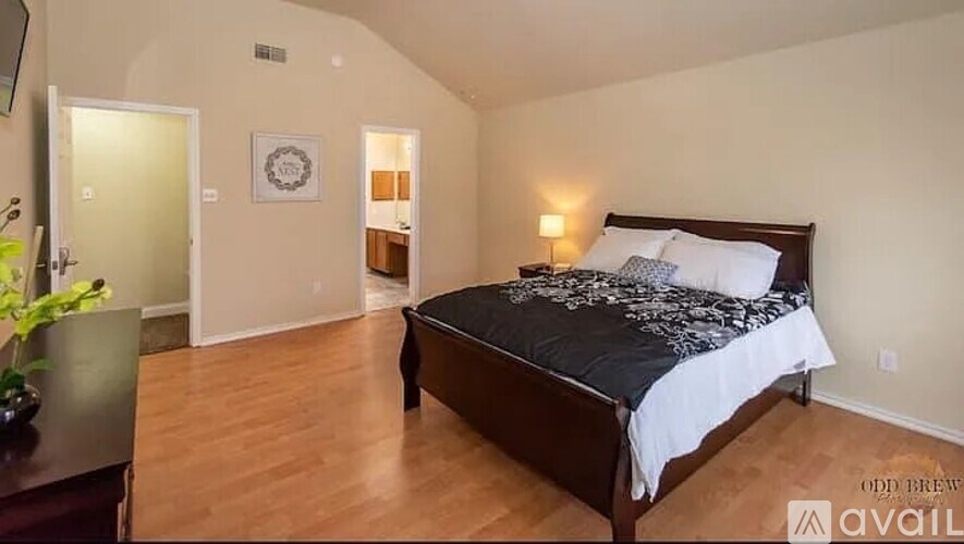 A bedroom with a bed, a nightstand, and a plant.