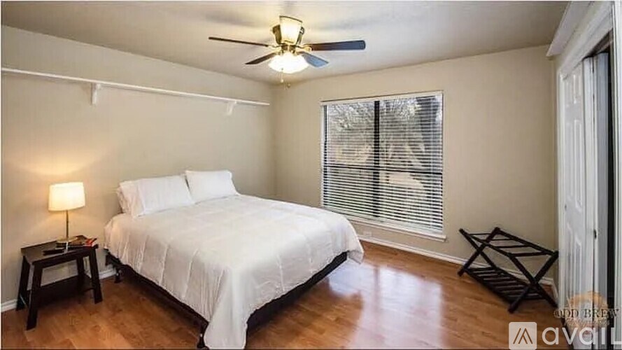 A bedroom with a bed, a ceiling fan, and a window with blinds.