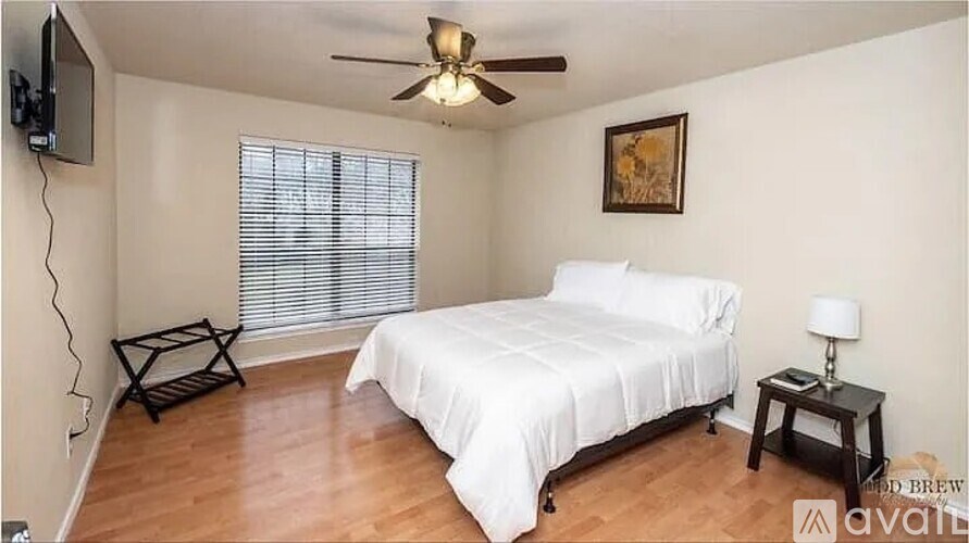 A bedroom with a bed, a ceiling fan, and a television.